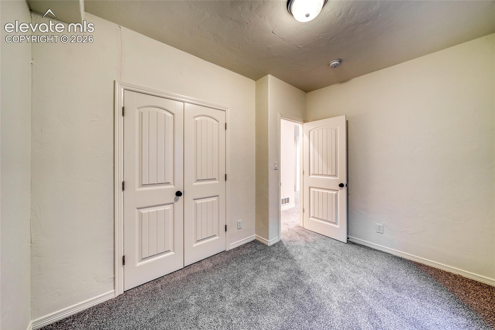 Interior room with neutral wall color and grey carpet flooring