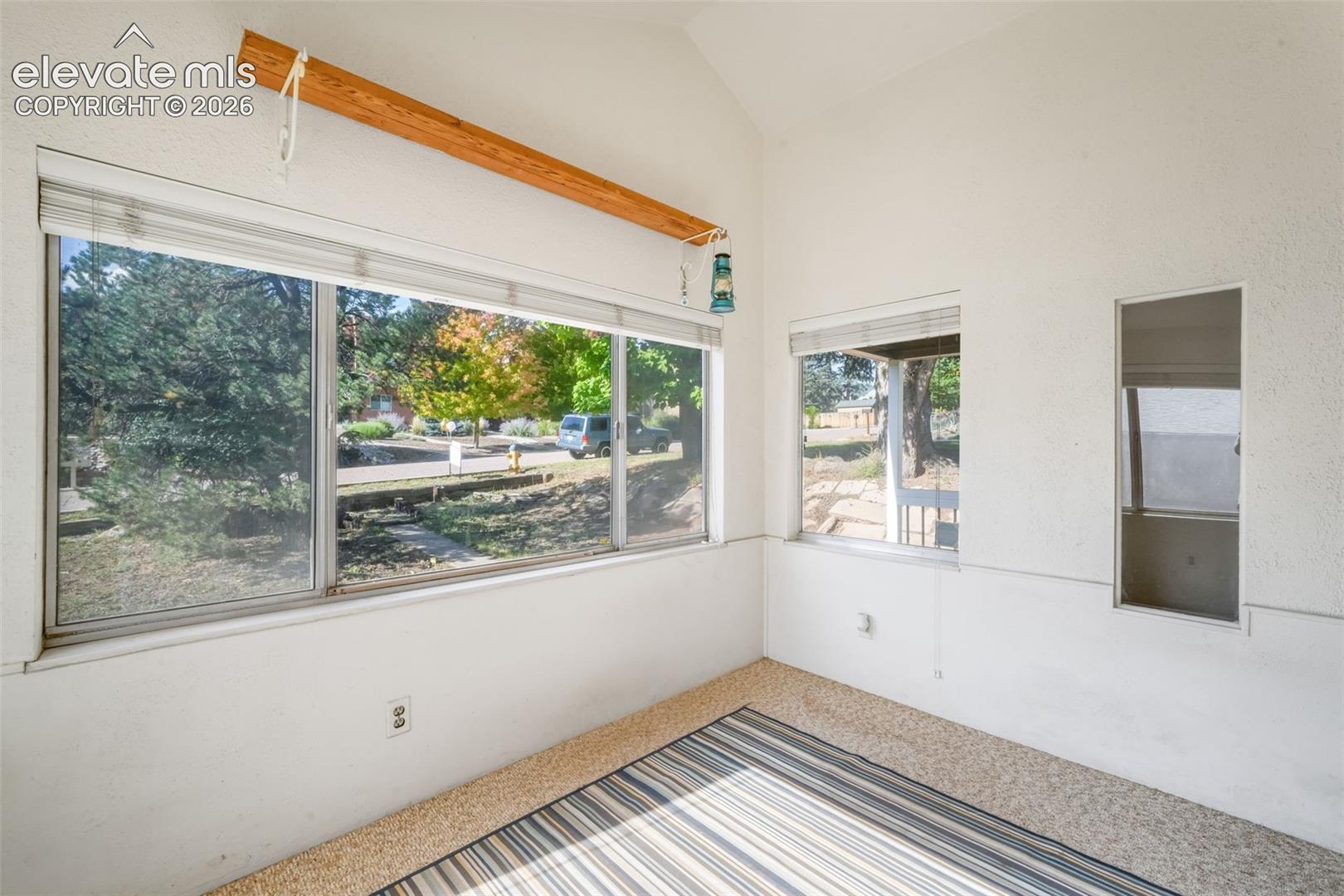 Vaulted ceiling sunroom with multiple windows and textured wall finish