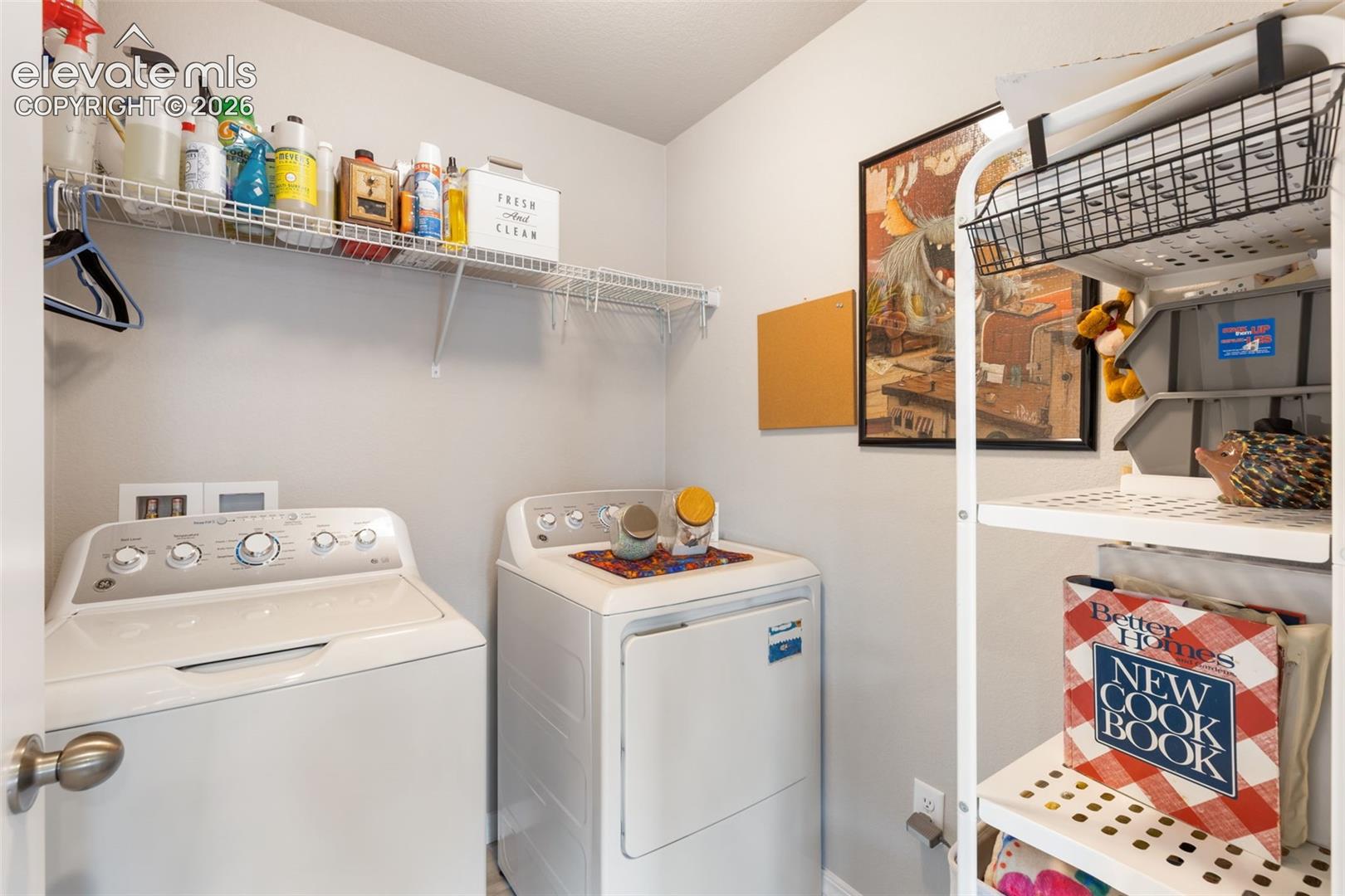 Dedicated laundry area featuring a washer and dryer, integrated wire shelving, and additional freestanding shelving