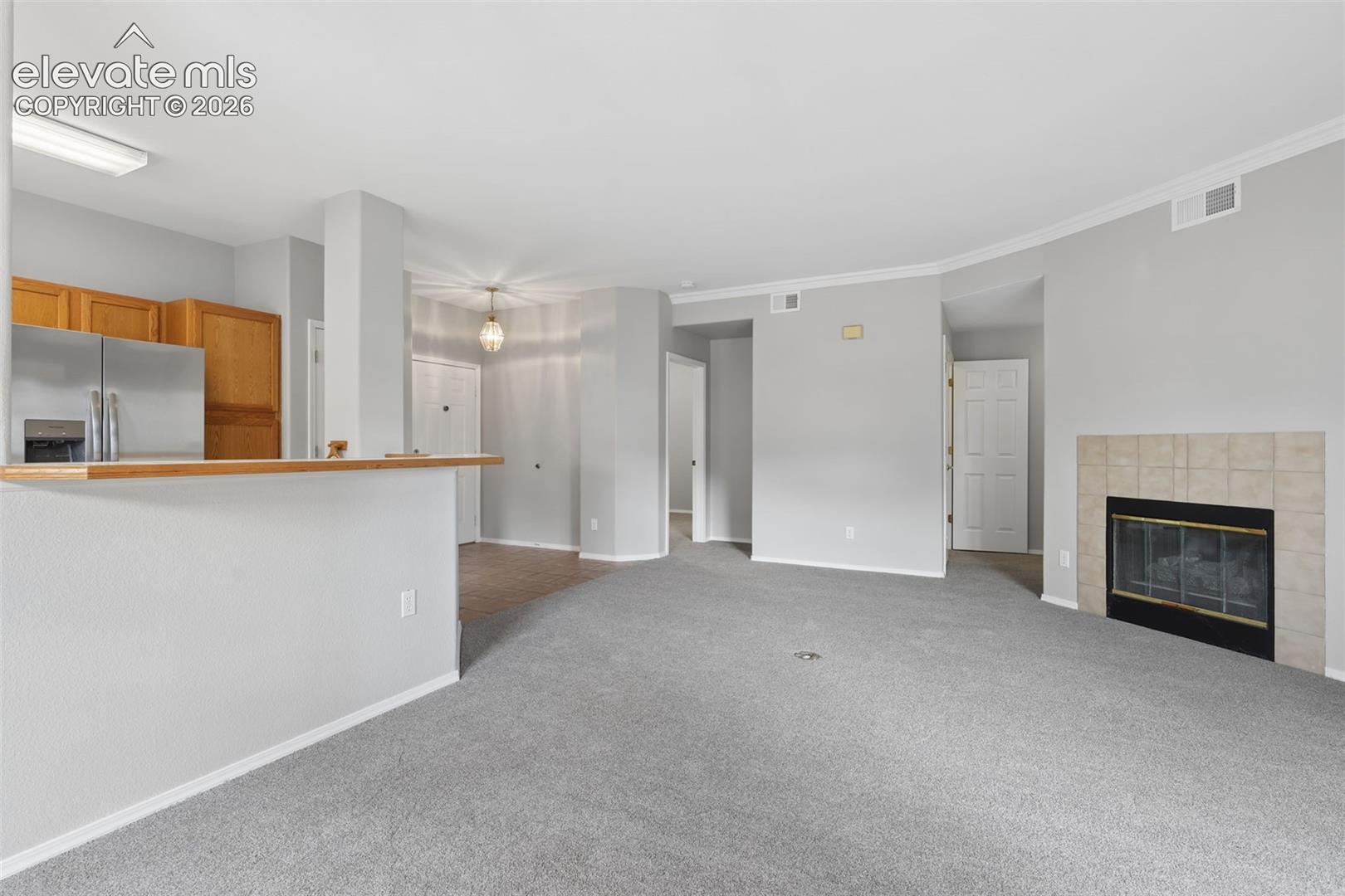 Warm wood cabinetry, stainless steel refrigerator, and a tiled fireplace