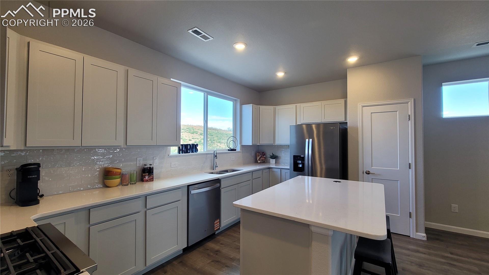 Kitchen with Quartz countertop, pantry, island providing additional seating, and stainless steel gas range, microwave, and dishwasher!
