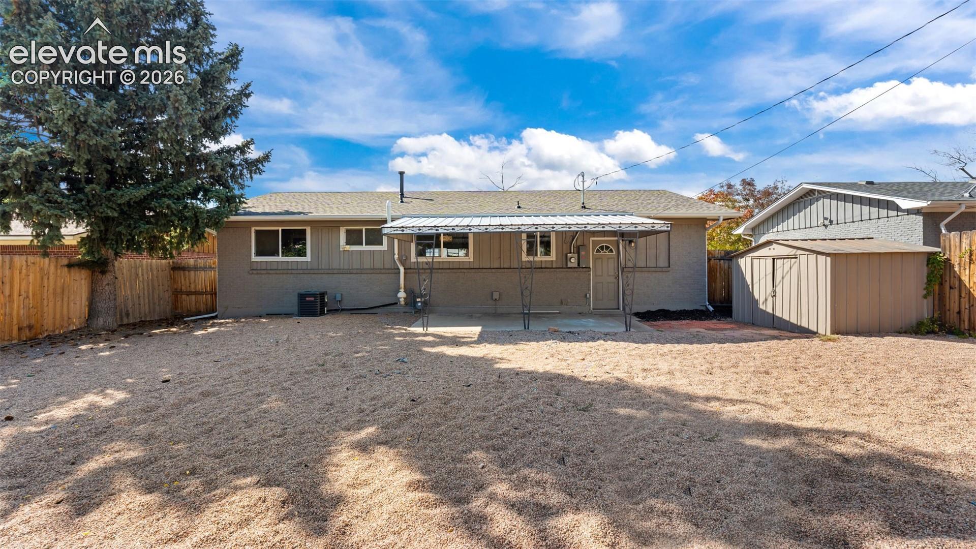 Rear exterior with a covered patio, multiple windows, and a detached storage shed