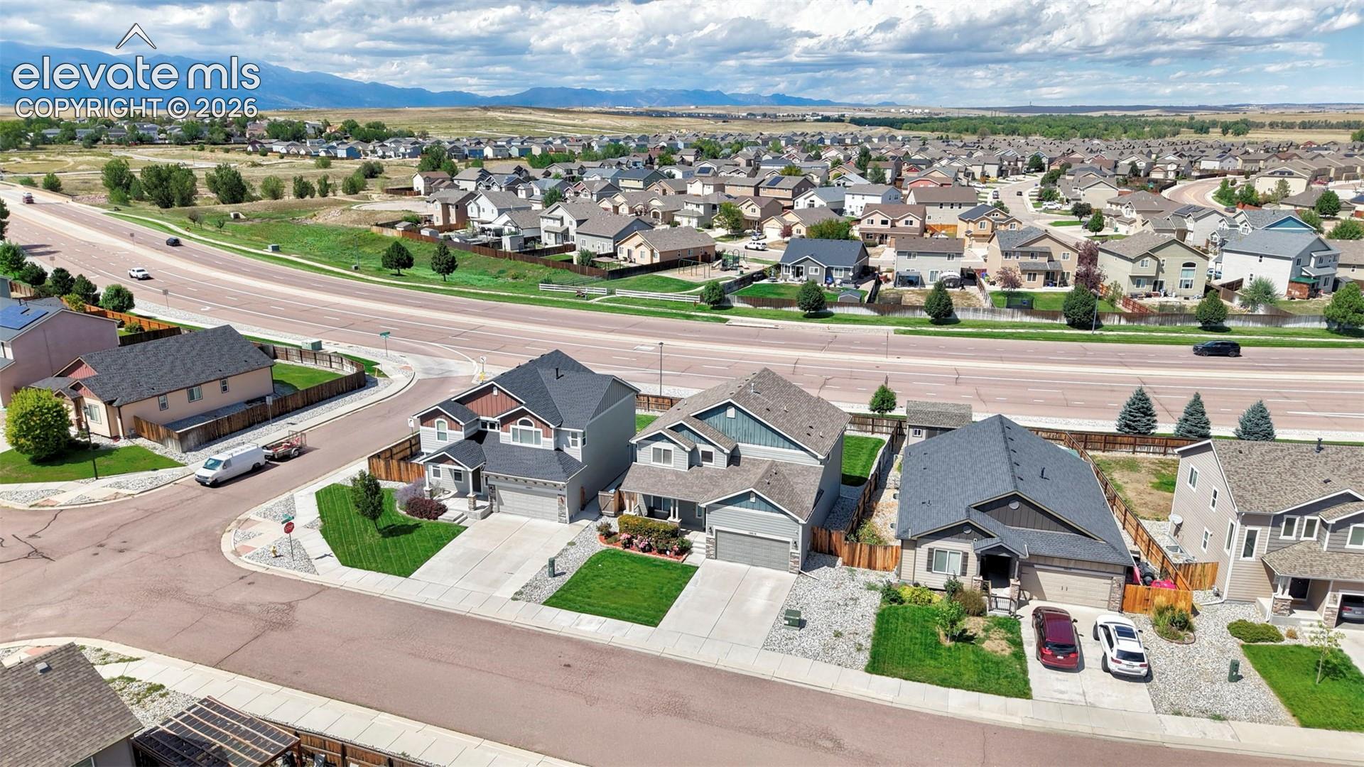 Residential neighborhood with paved roads, manicured lawns, and visible mountain range