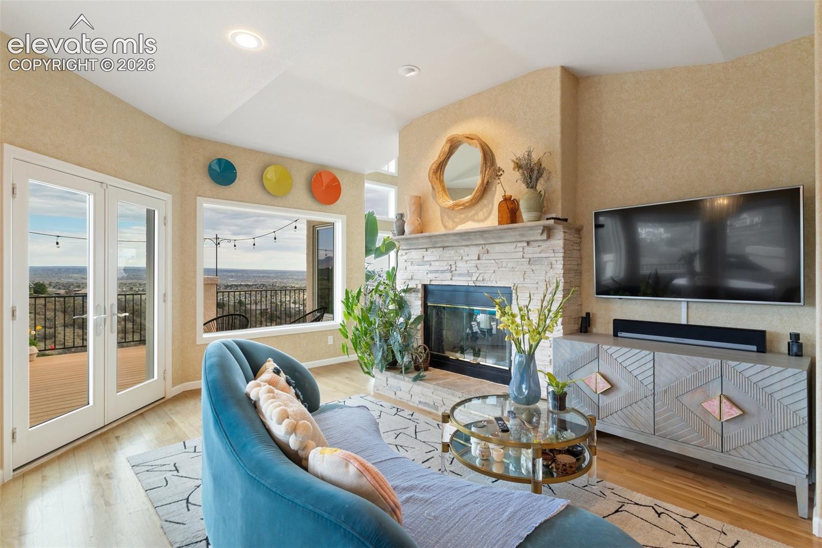 Spacious living area featuring a stone-clad fireplace, light wood-finish flooring, and recessed lighting