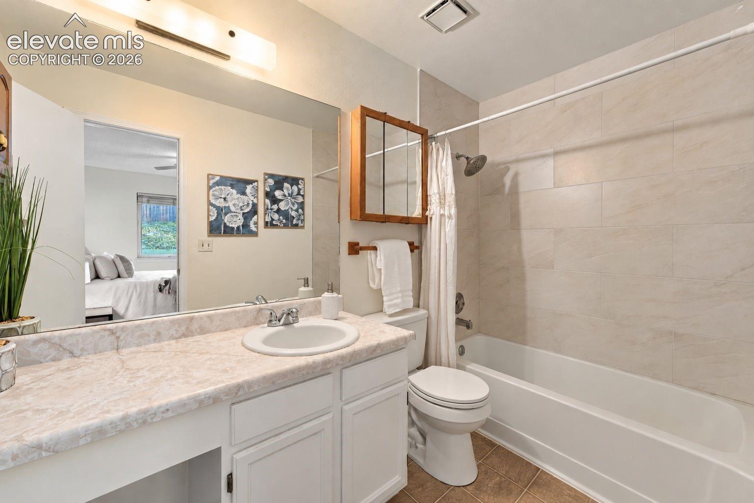 Bathroom featuring a vanity with a light-toned stone countertop, recessed lighting, a medicine cabinet, and a shower-tub combination with large-format wall tile