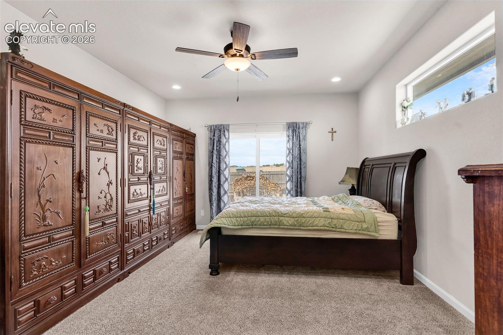 Spacious room featuring extensive built-in dark wood cabinetry with intricate carvings, a ceiling fan with integrated lighting, and recessed ceiling lights