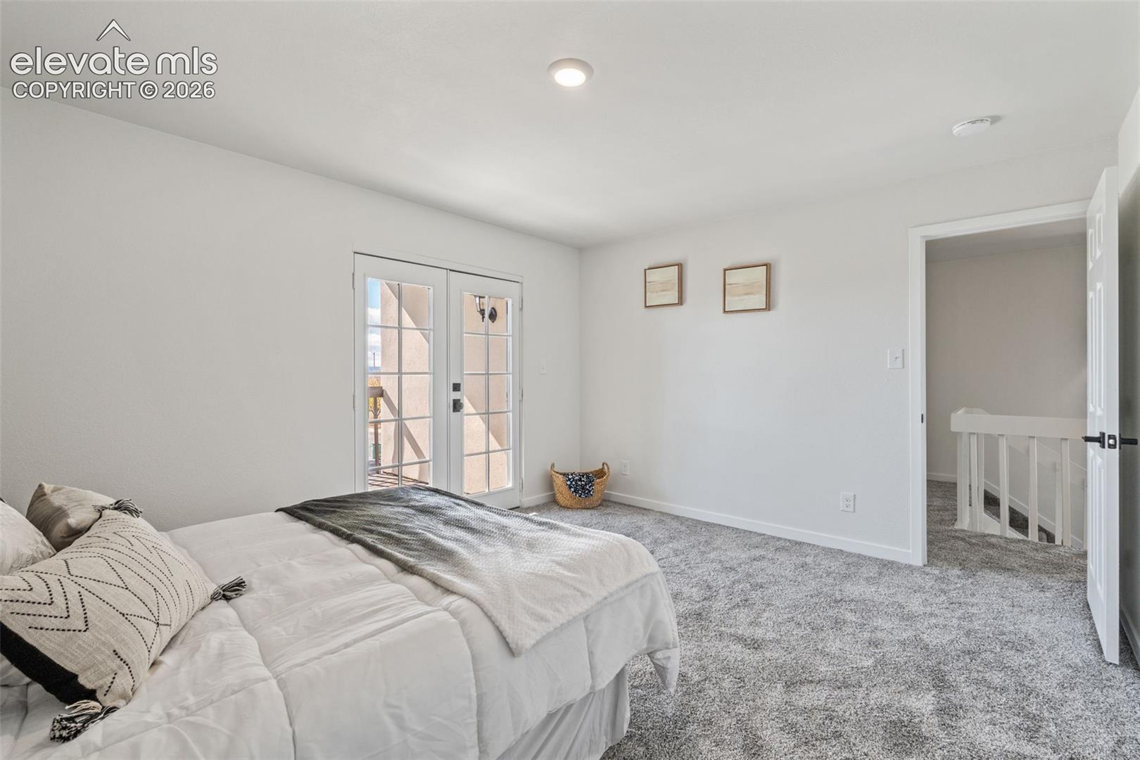 Neutral-toned carpeting, glass-paned French doors, and recessed lighting