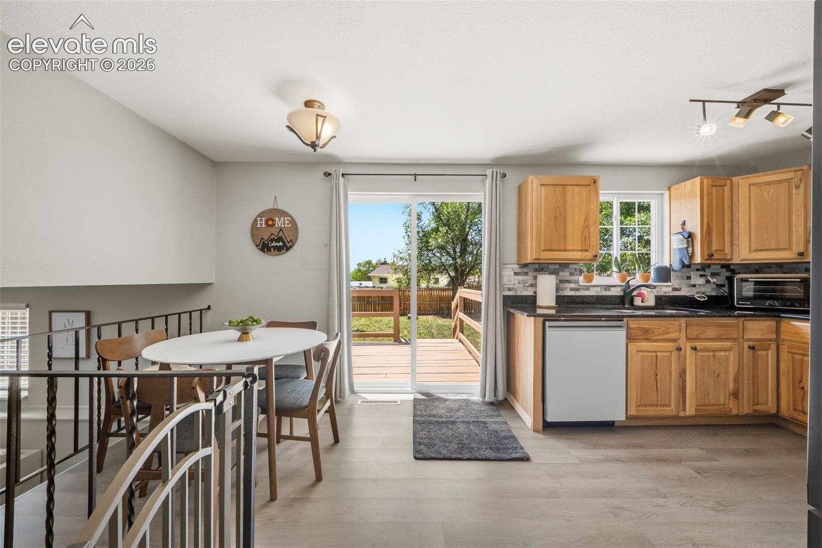Kitchen with wood-finish cabinetry, dark countertops, and a tile backsplash