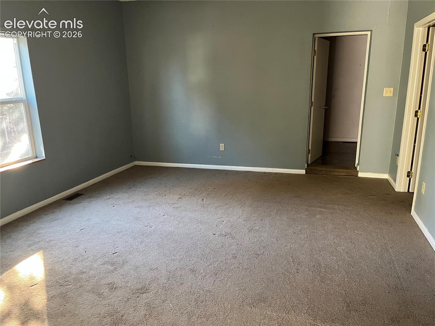 Neutral wall paint, plush carpeting, a multi-pane window, and interior door frames