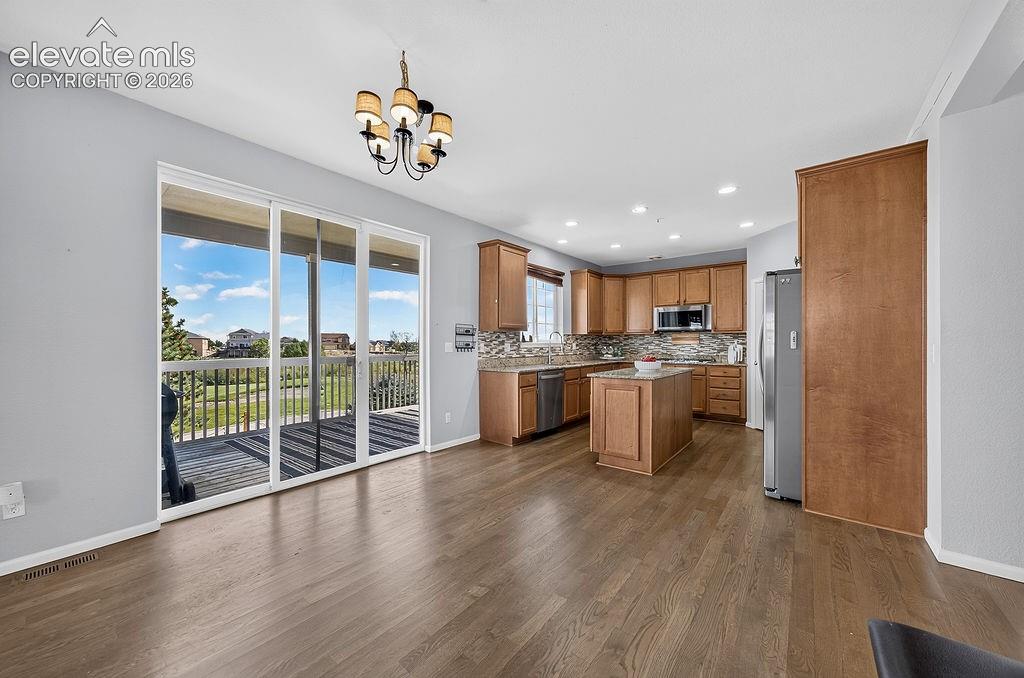 Wood-finish flooring throughout, kitchen with wood cabinetry, stainless steel appliances, and a central island