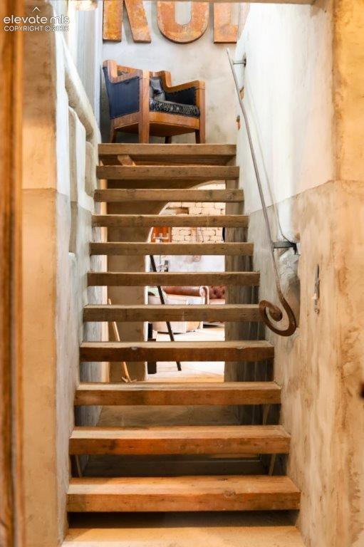 Open-tread staircase featuring wood-finish steps and a wrought-iron handrail