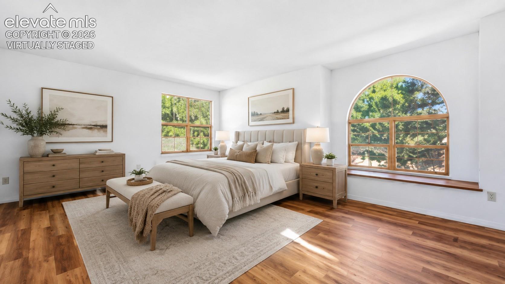 Virtually staged primary suite with an arched window and new LVP flooring at , Colorado Springs, CO.