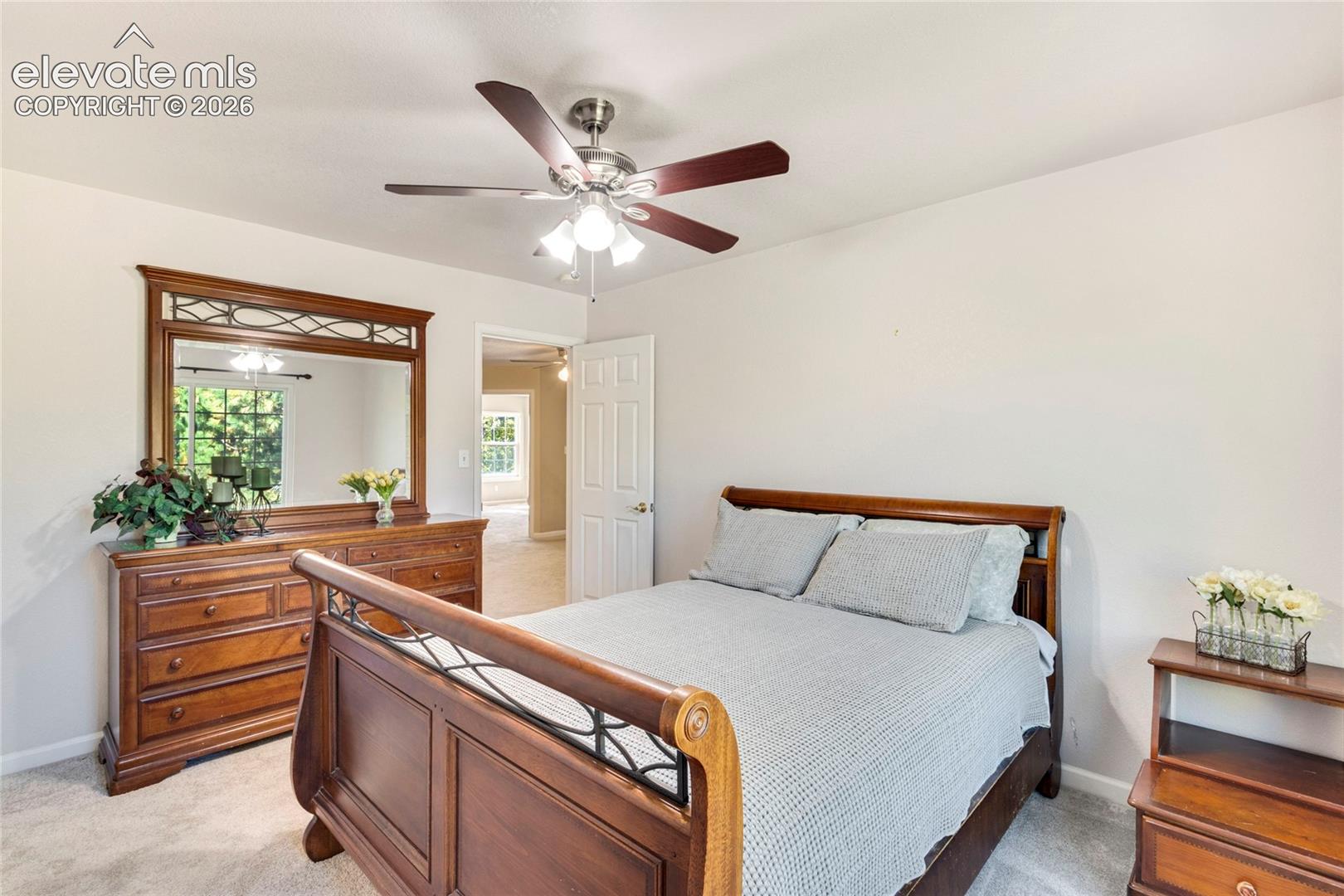 Neutral-toned room featuring a central ceiling fan with integrated lighting, carpeted flooring, and a six-panel interior door
