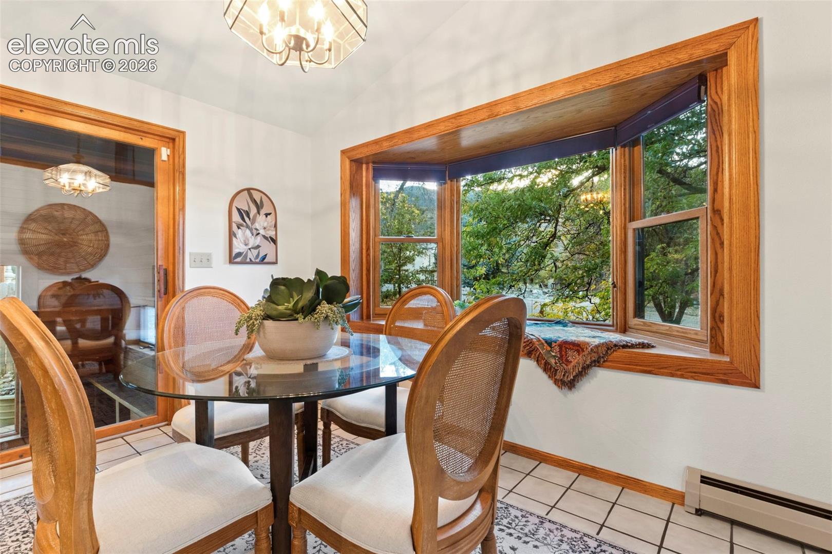 Large bay window with wood trim, ceramic tile flooring, and geometric overhead light fixture