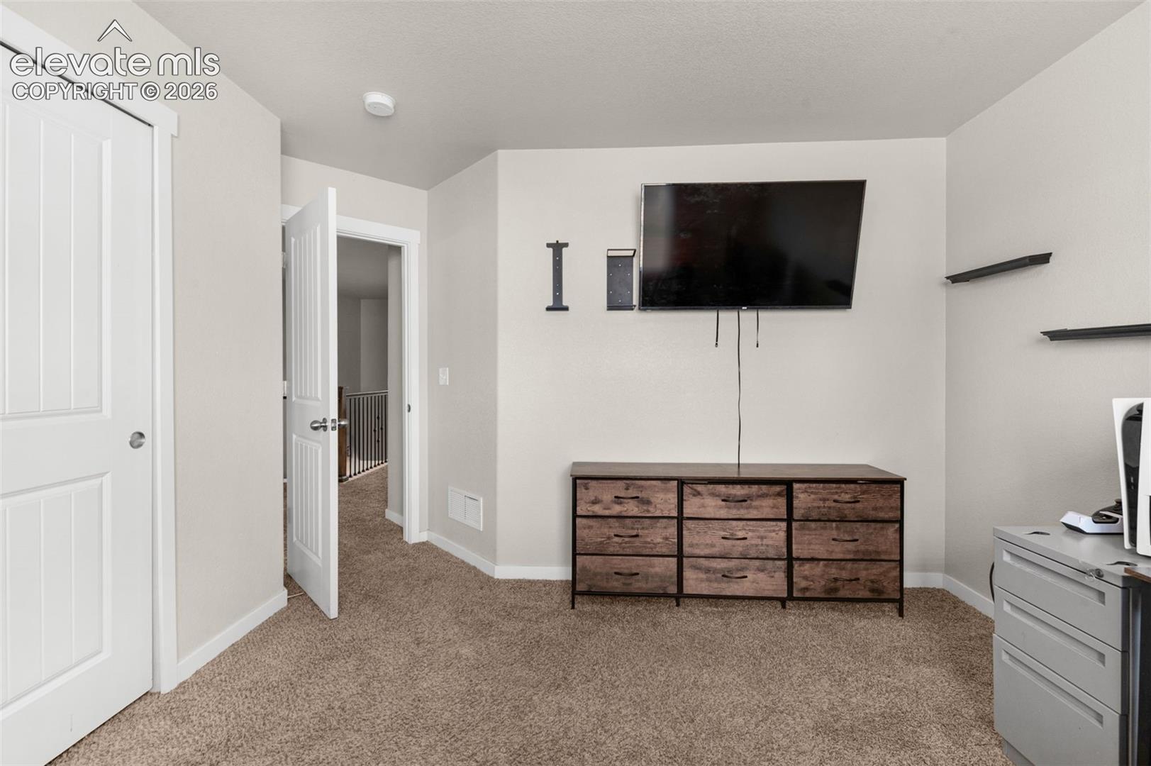 Neutral wall-to-wall carpeting, three-panel interior doors, and two wall-mounted floating shelves