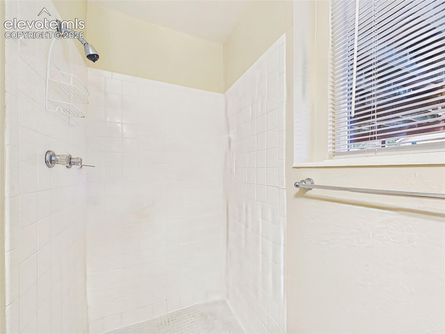 Functional bathroom featuring a walk-in shower with tile surround and a window for natural light and ventilation.