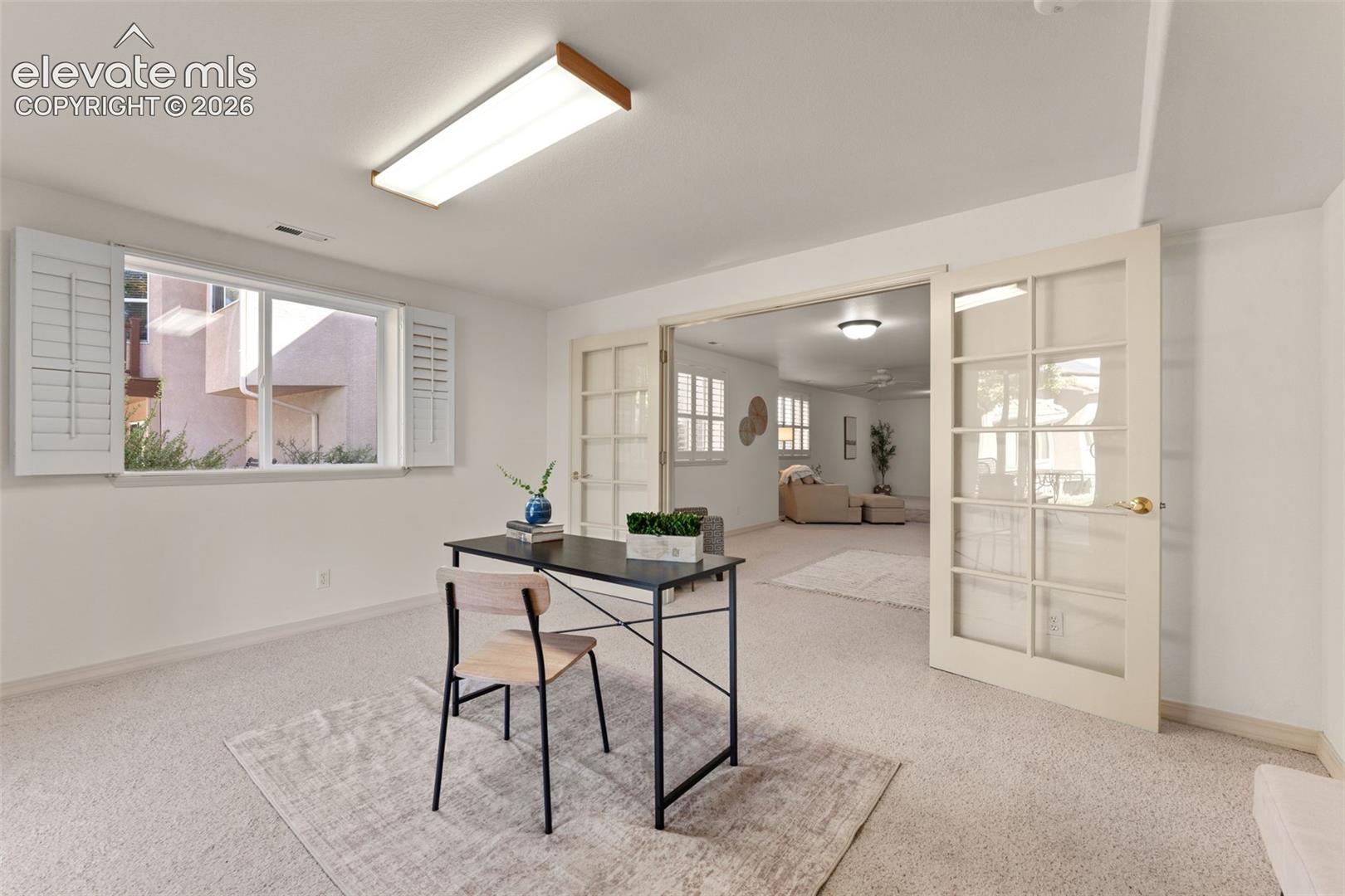 Room featuring neutral carpeting, white interior wall shutters, and French doors with glass panes