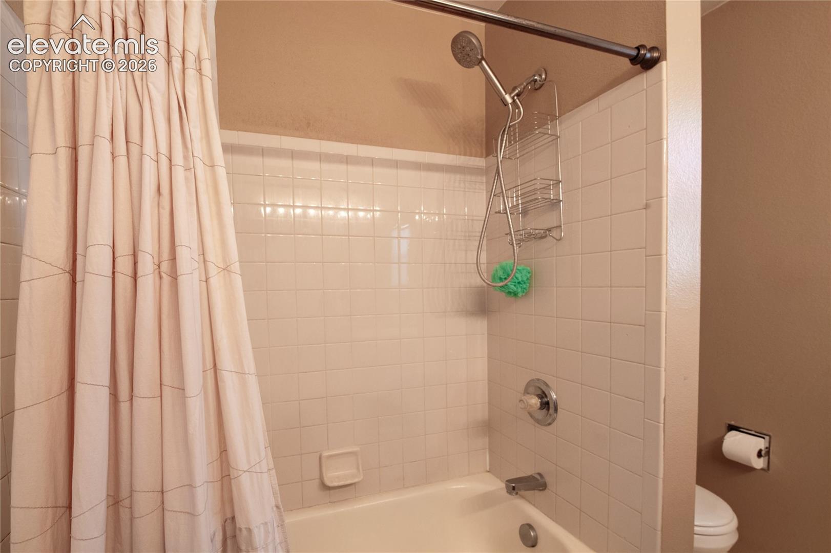 Bathtub with white subway tile surround, chrome fixtures, and a shower curtain rod