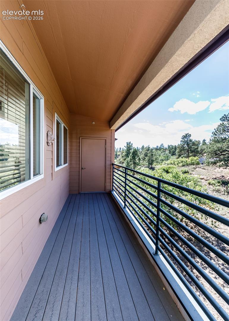 Covered balcony featuring composite decking, horizontal metal railing, and exterior storage door