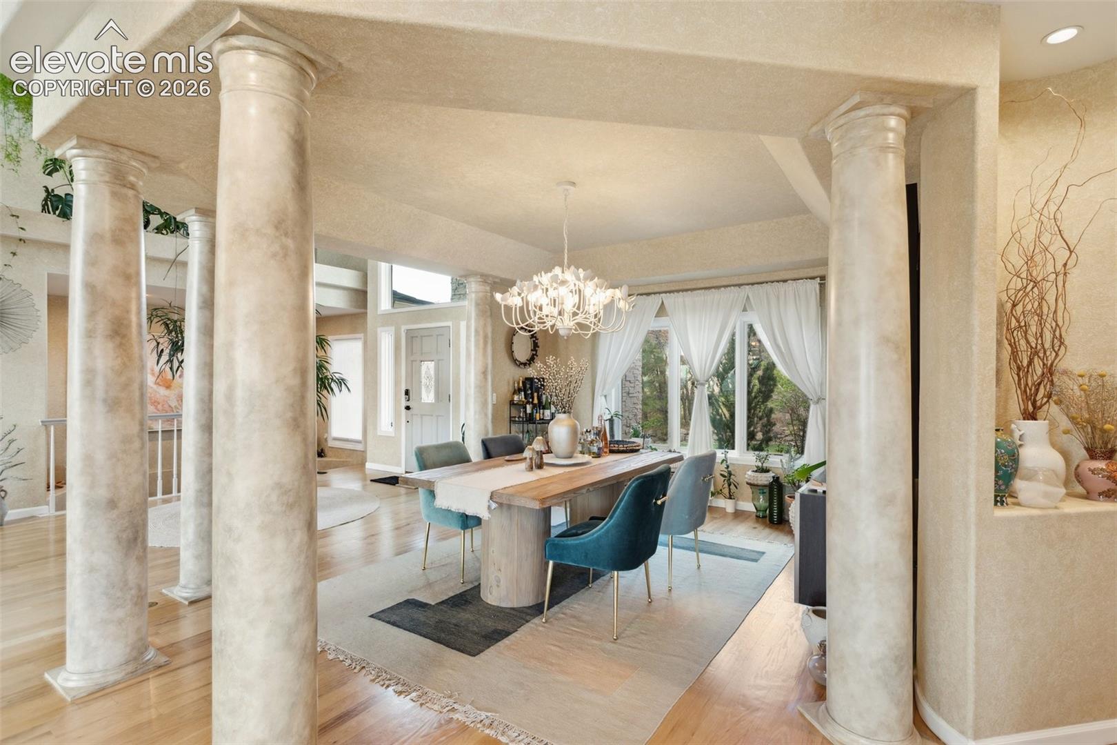 Dining area featuring a crystal chandelier, wood-finish flooring, and a large window with ample natural light