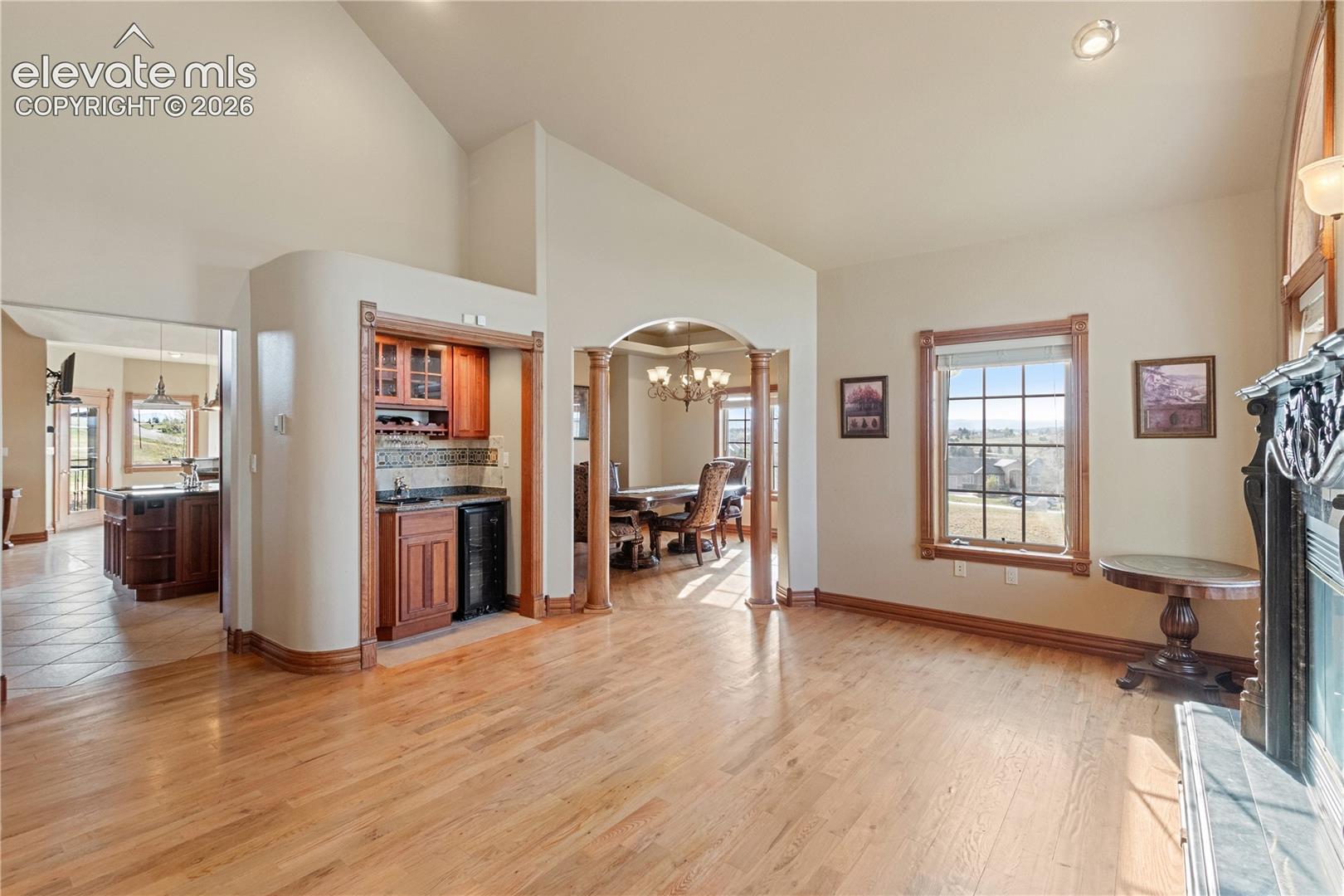 Living room to right of entryway with wet bar, looking into dining room and kitchen