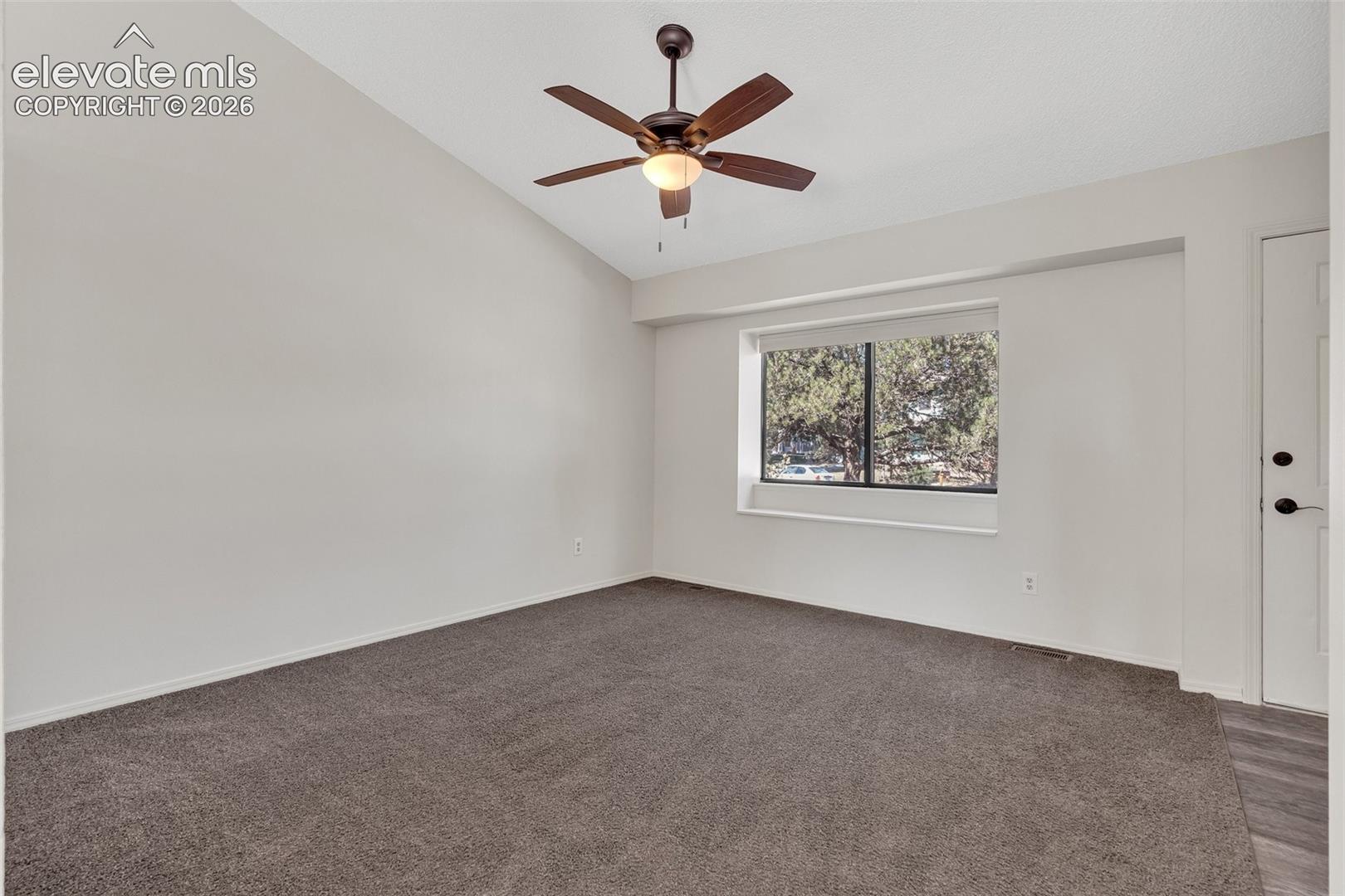 Vaulted ceiling with a ceiling fan, neutral carpet, and a window with a deep sill