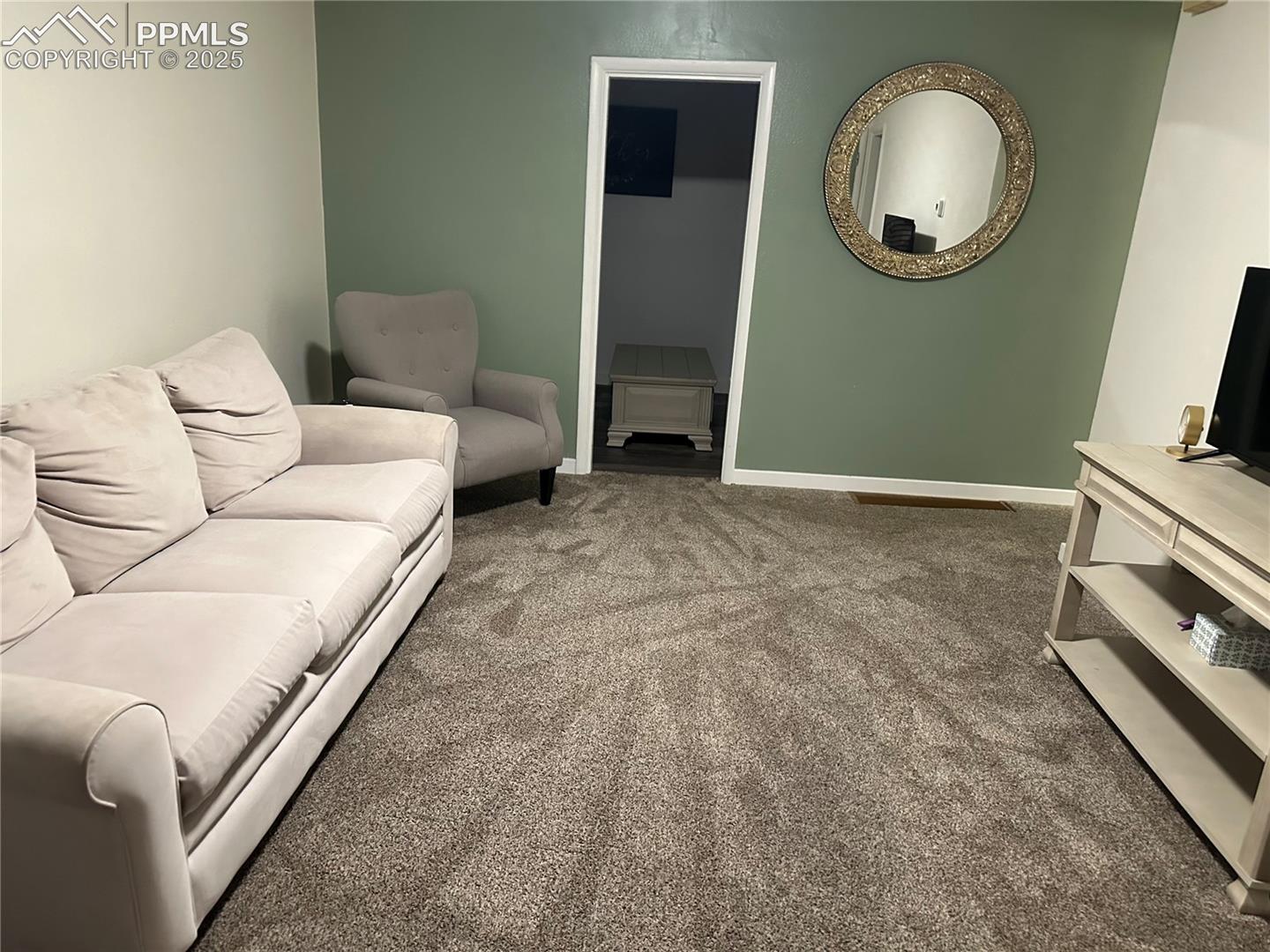 Carpeted living area featuring baseboards