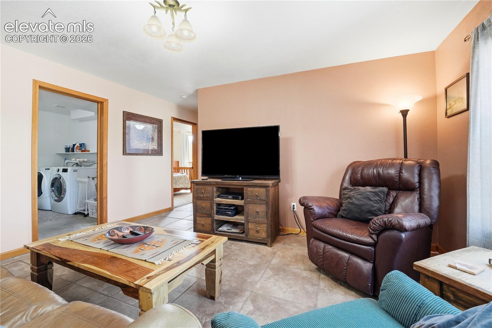 Tile flooring, wood-finish trim, built-in media console, ceiling-mounted light fixture, laundry area