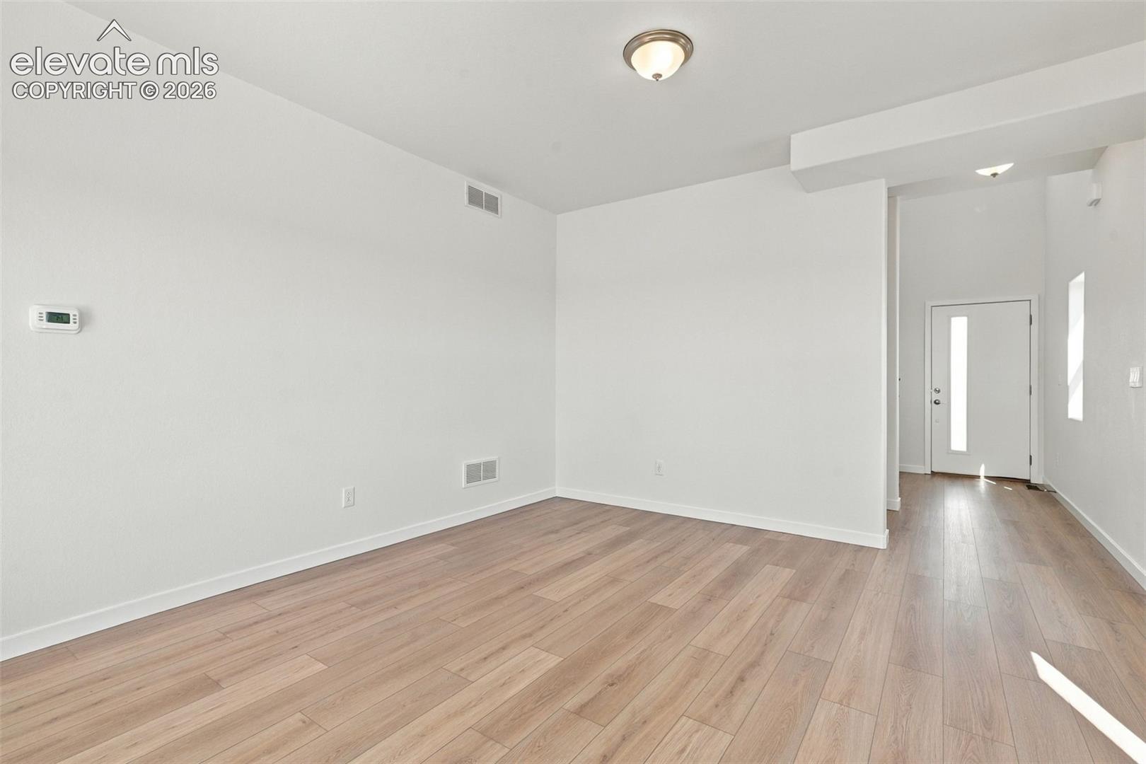 Open concept living space featuring wood-finish flooring, white walls, and a contemporary flush-mount ceiling light