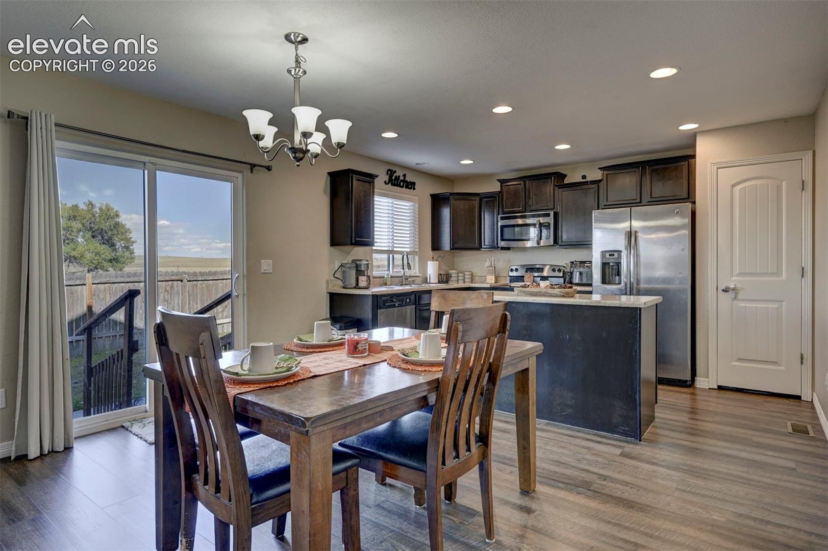 Kitchen area featuring dark wood cabinetry, stainless steel appliances, a center island with a light-toned countertop, and recessed lighting