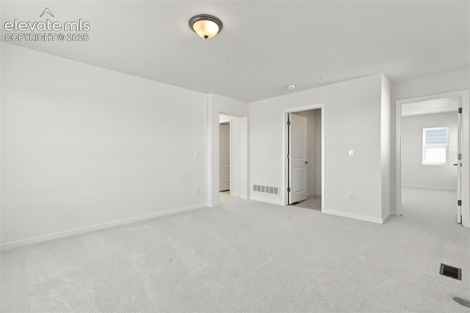 Light-toned wall-to-wall carpeting, white painted walls, and ceiling-mounted light fixture