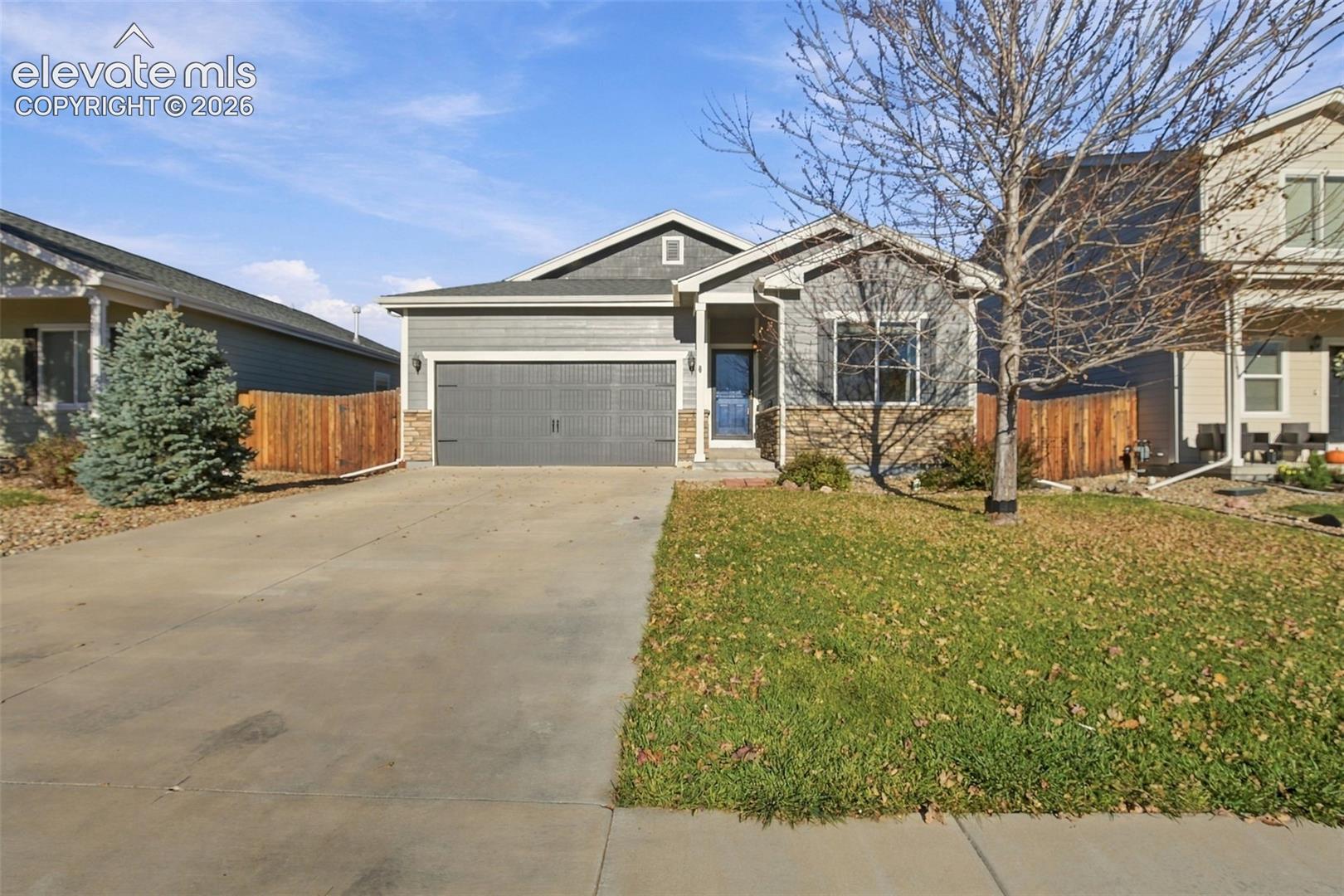 Single-story exterior featuring a horizontal siding and stone veneer facade, an attached two-car garage, and a concrete driveway