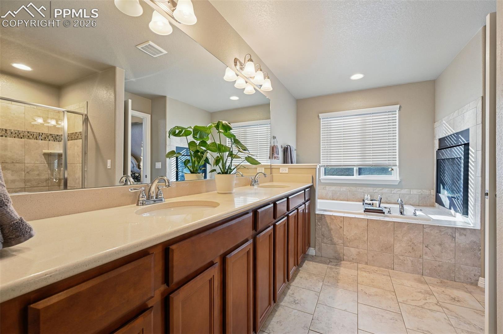Full bath with a stall shower, double vanity, and a garden tub