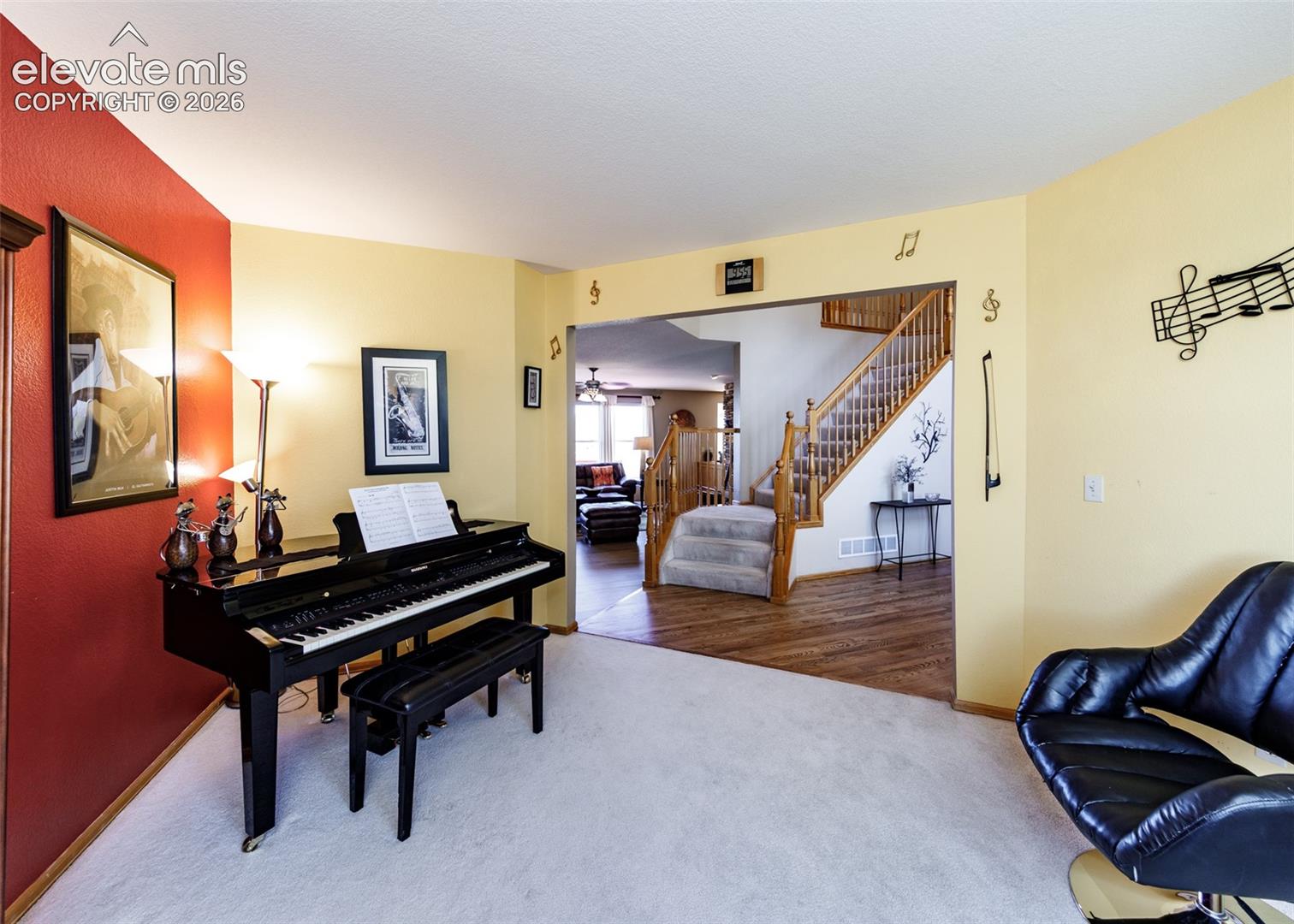 Multi-level interior featuring wood-finish flooring, a carpeted staircase with wood banister, and an arched entryway