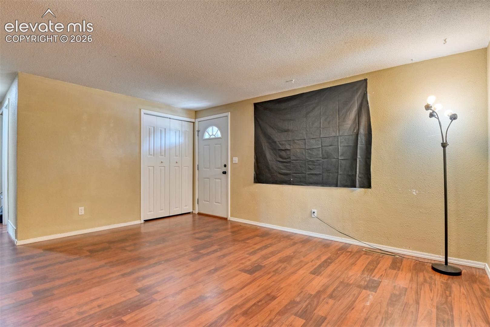 Spacious interior with wood-finish flooring, light-toned wall paint, and white baseboards