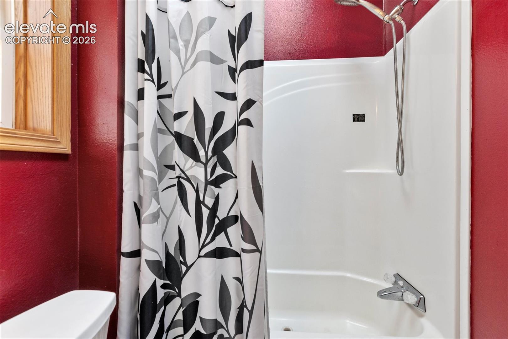 White fiberglass tub and shower combination with a curved basin and chrome fixtures