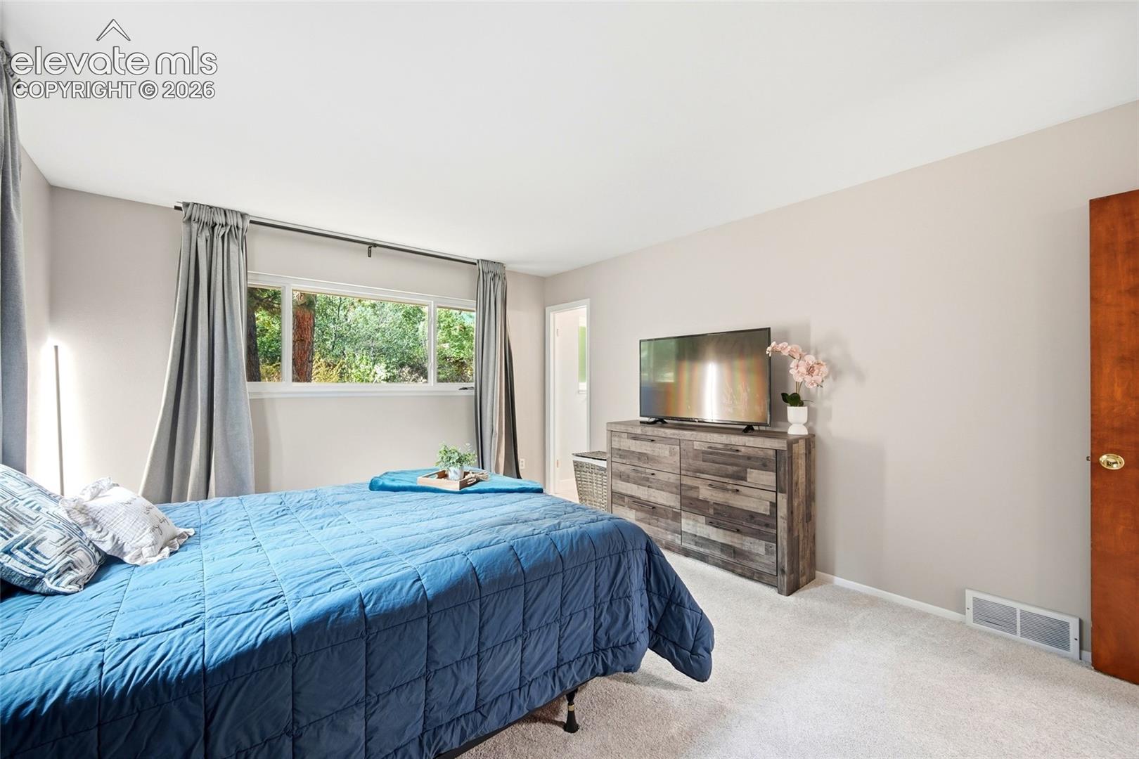 Neutral-toned interior space featuring wall-to-wall carpeting and a horizontal sliding window with natural outdoor visibility