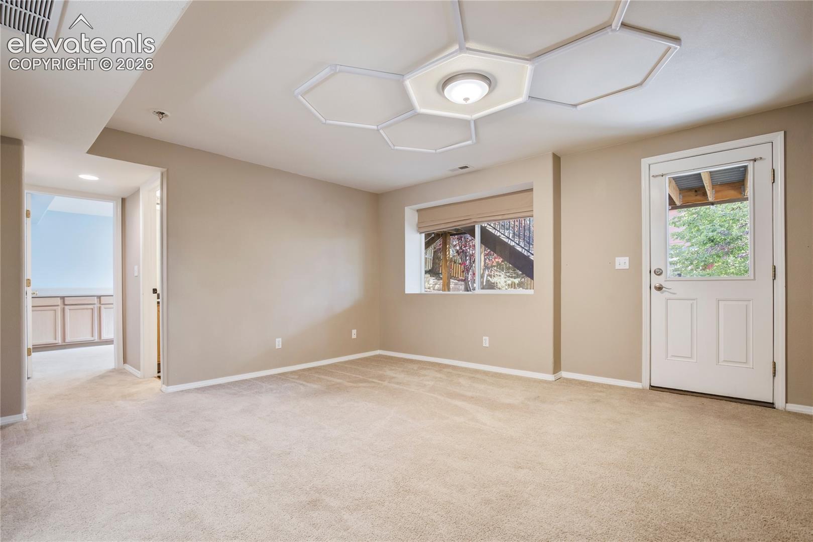 A private exterior door opens from the lower-level family room to the covered patio, providing convenient access to the fenced backyard + outdoor gathering spaces.