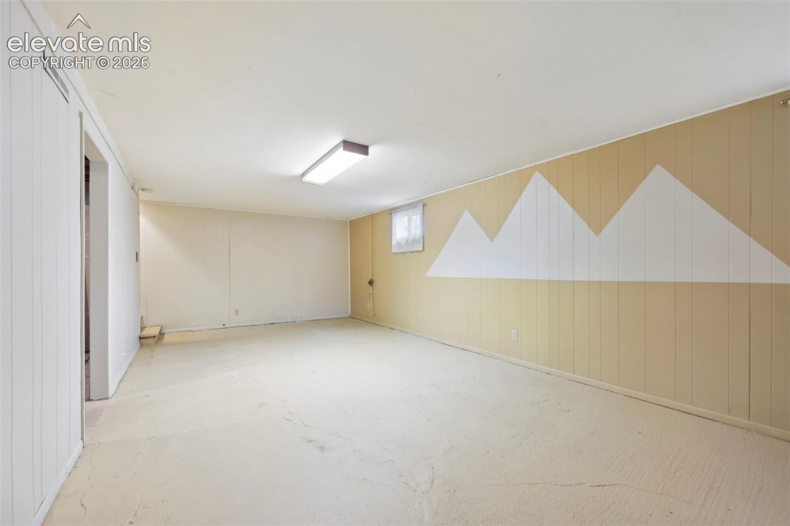 Spacious room featuring light-colored walls, a drop ceiling with recessed lighting, and a window with natural light