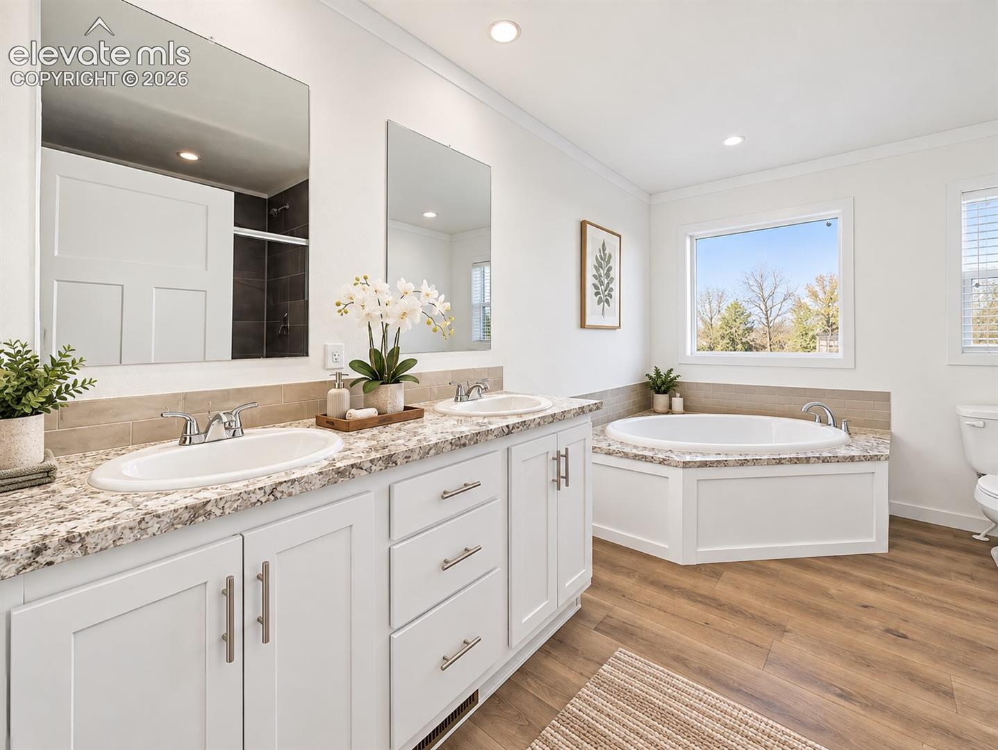 Primary Bathroom – Another view highlights the dual-sink vanity, abundant counter space, soaking tub, and bright, open layout.