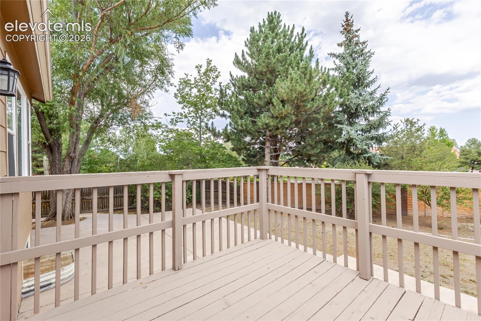 Spacious composite deck featuring horizontal and vertical railings, composite decking surface, and expansive sightlines overlooking mature landscaping and evergreen trees