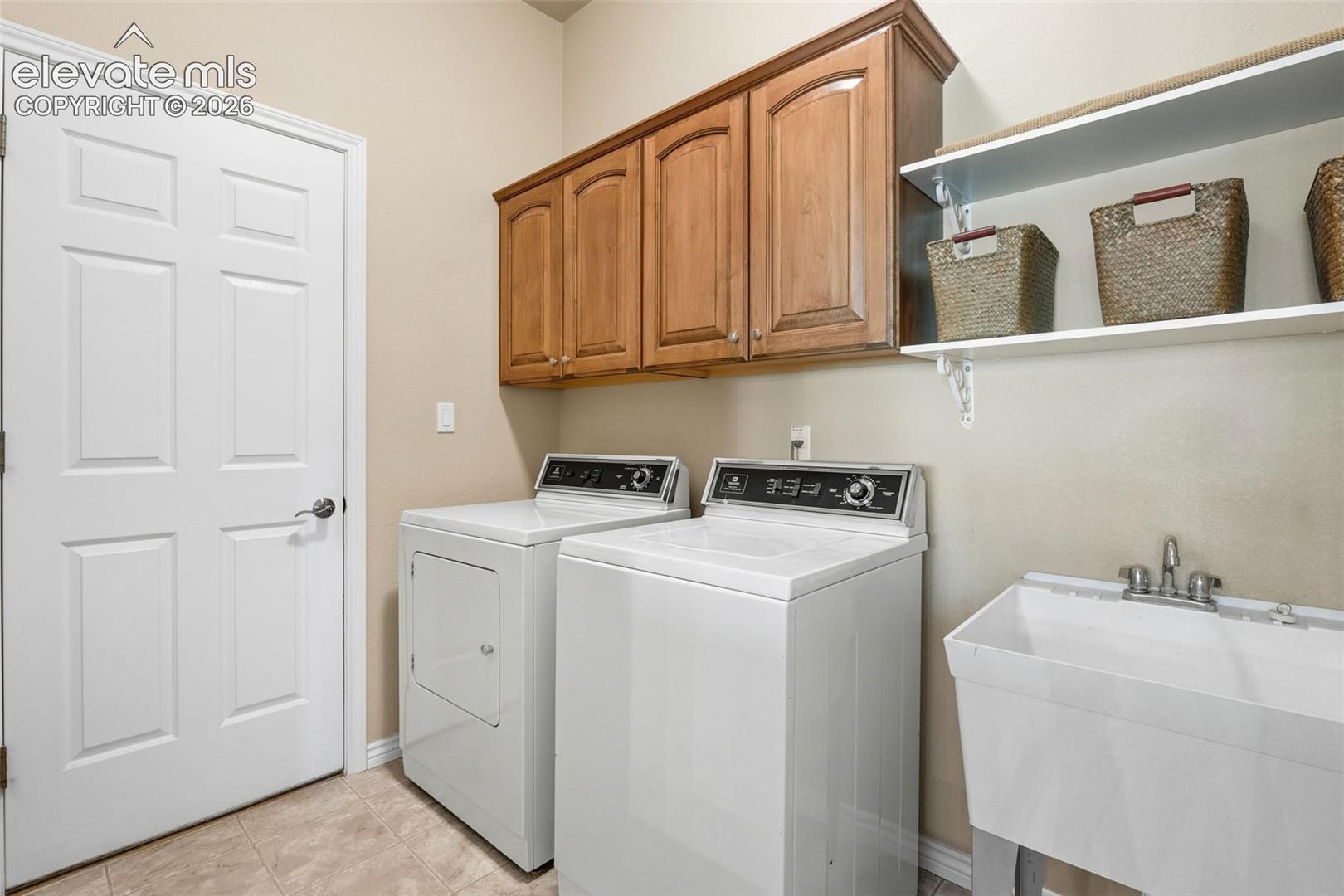 LAUNDRY ROOM WITH CABINETS, OPEN SHELVING AND UTILITY SINK (AND DOOR TO GARAGE)