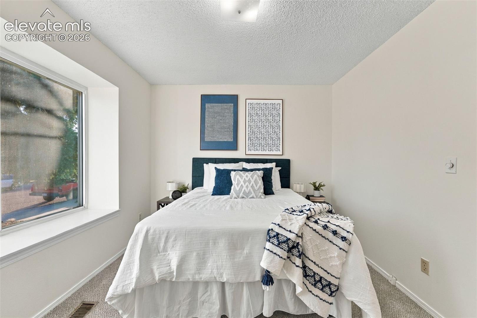 Neutral-toned room featuring a large bay window, wall-to-wall carpeting, and a flush-mount ceiling light fixture