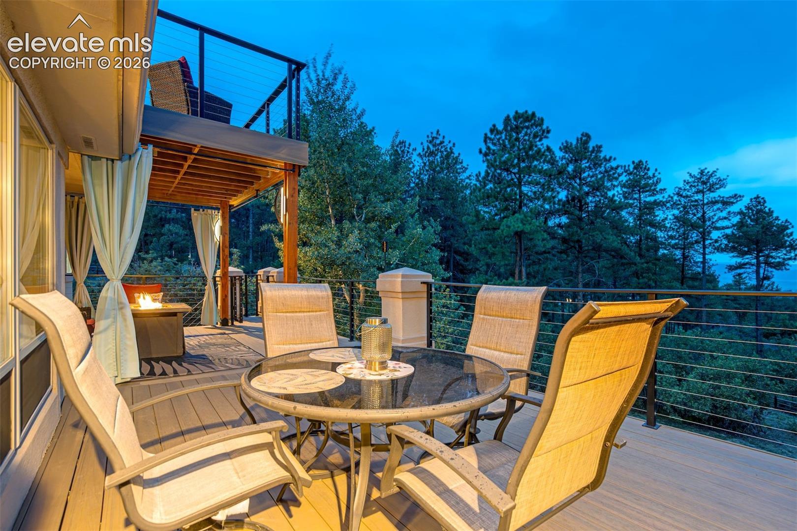 Expansive outdoor deck featuring wood-finish flooring, cable railing, and a built-in fire feature