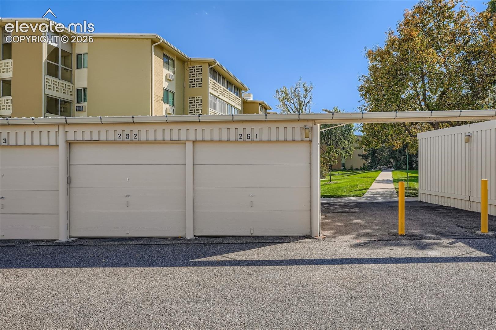 Individual garage spaces with roll-up doors and a paved asphalt drive