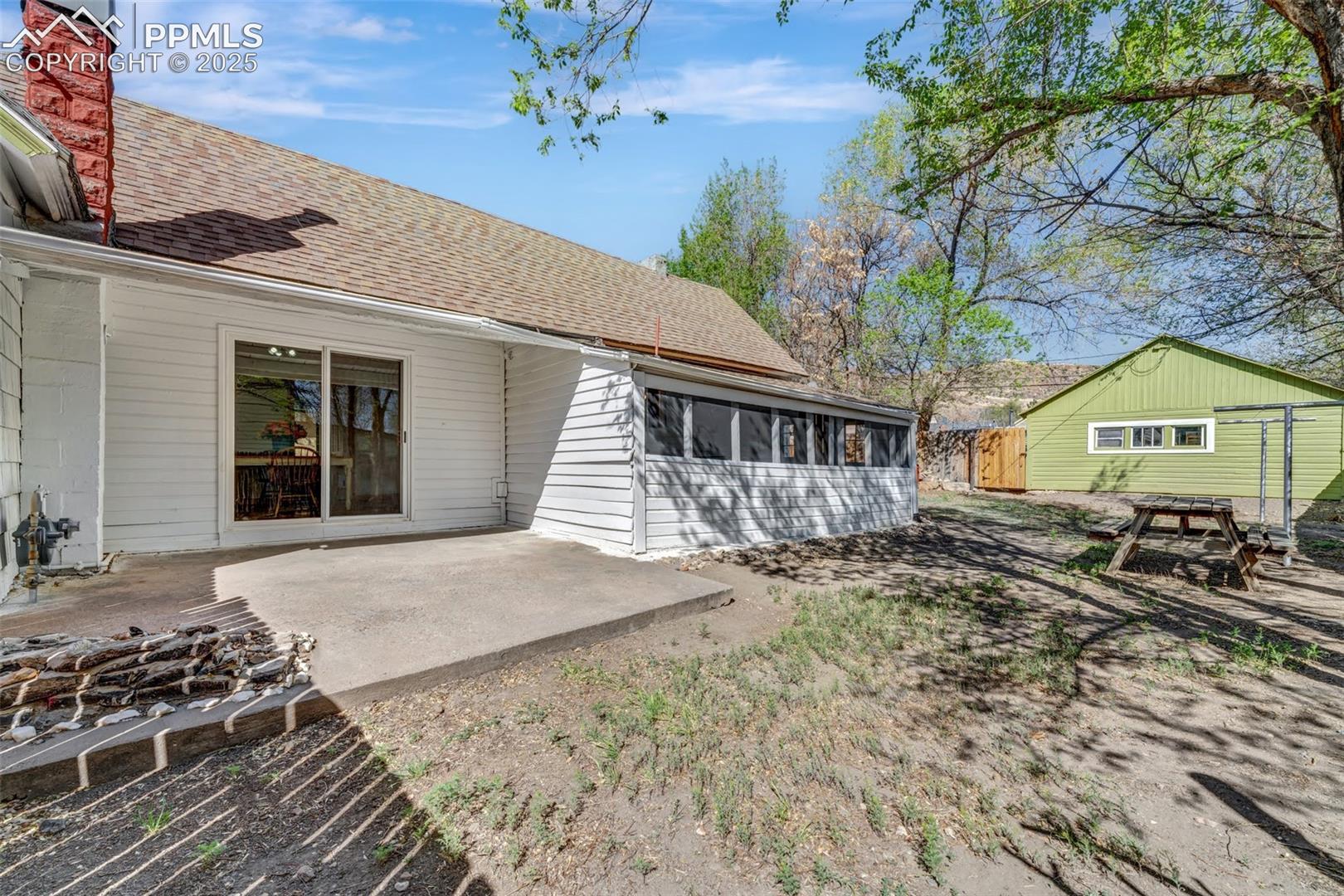 Screened in Porch, Cement Patio, and Green Garage in Background