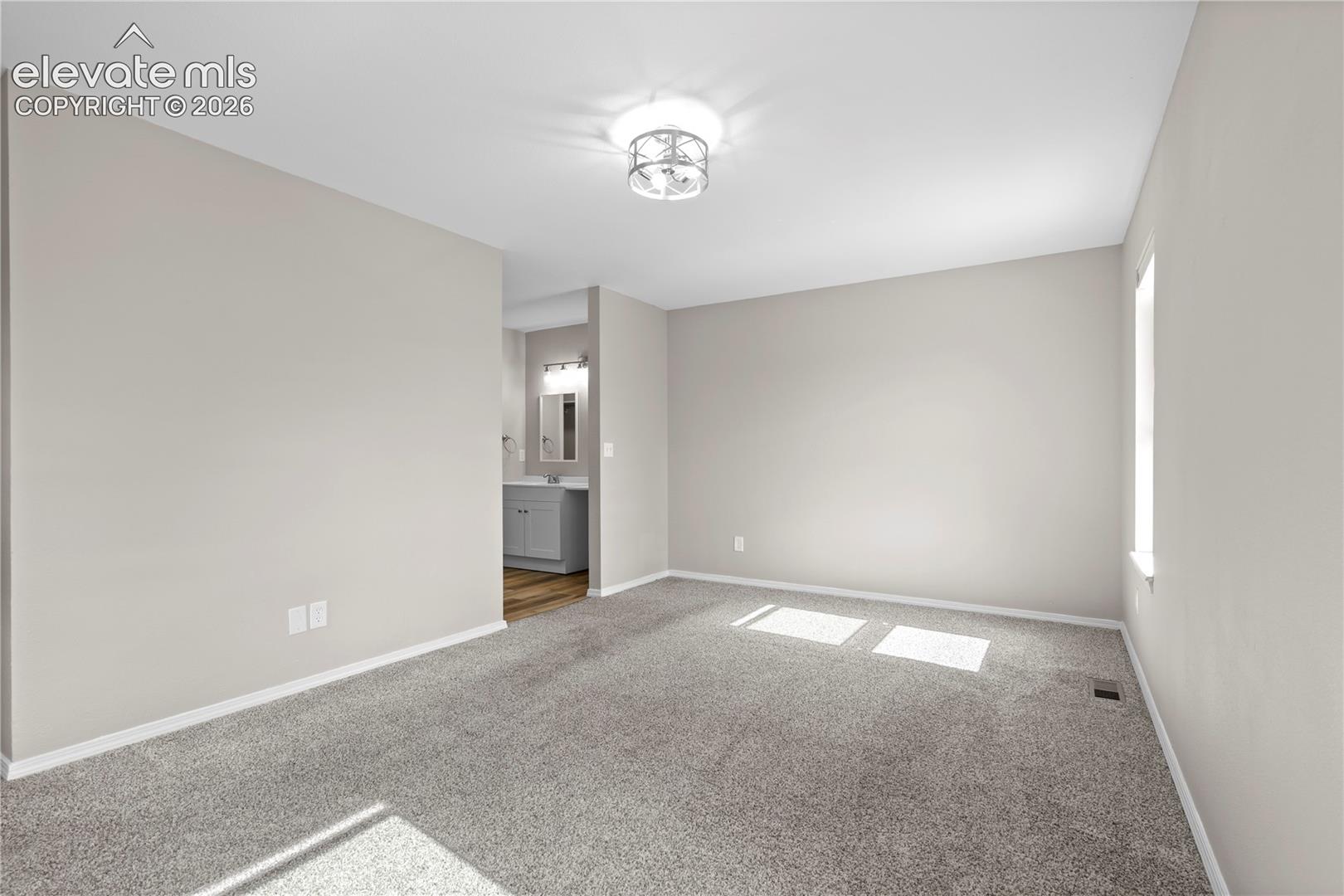 Neutral wall color, wall-to-wall carpeting, and a polished metal flush-mount light fixture