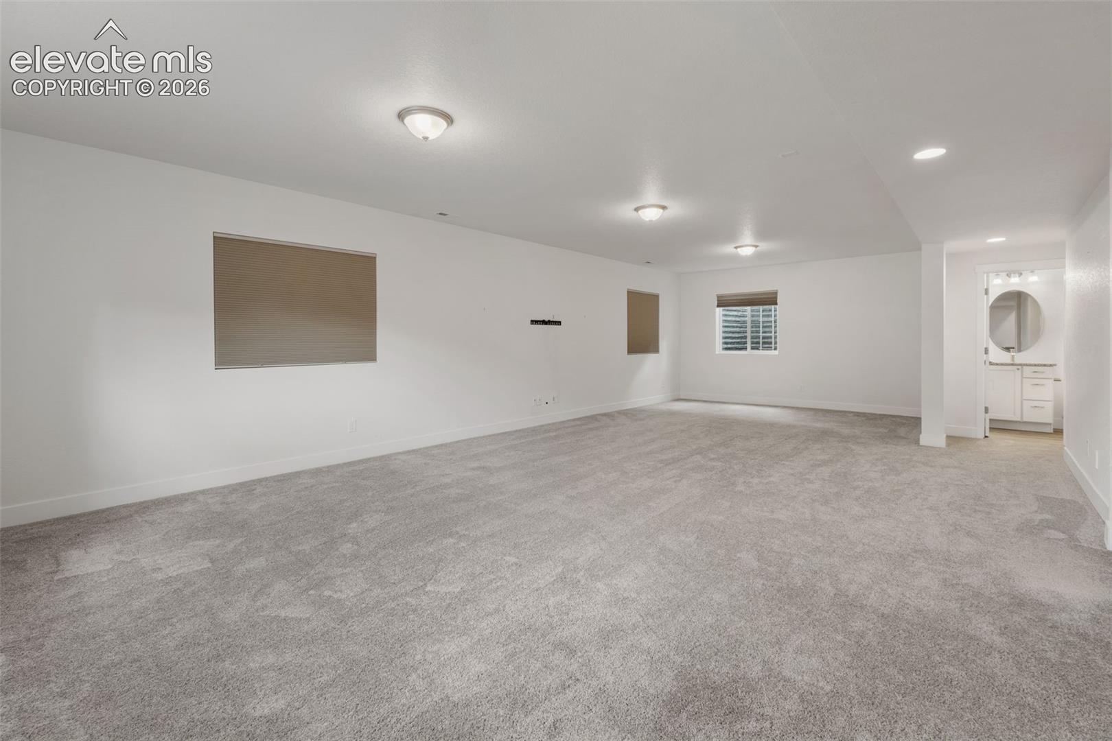 Spacious finished lower level featuring recessed lighting, light gray carpeting, and a powder room