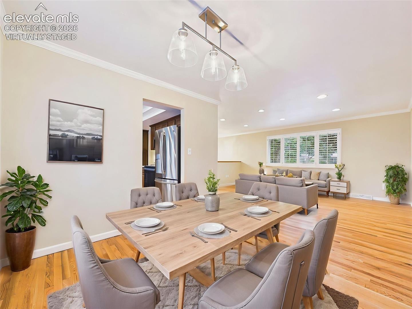 (Virtually Staged) Living & Dining Areas – Expansive living room with hardwood floors, recessed lighting, and large windows that create a bright, open atmosphere flowing into the dining space.