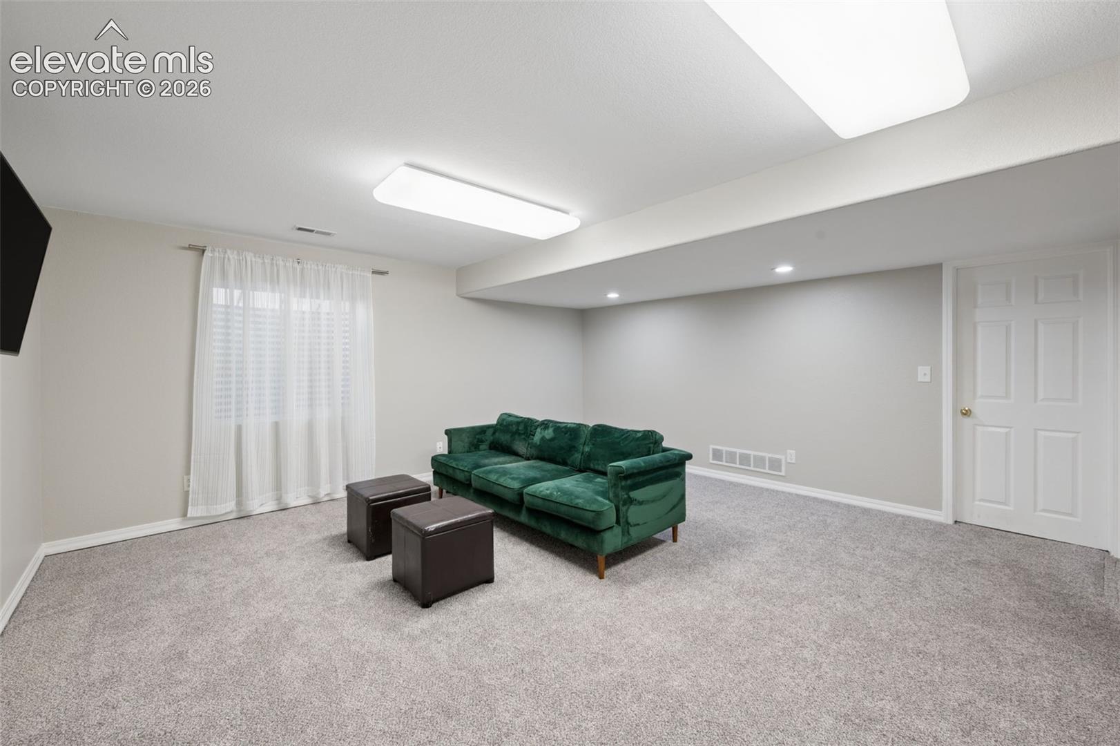 Neutral-toned interior space featuring neutral wall-to-wall carpeting, recessed and rectangular flush-mount lighting, and a six-panel interior door